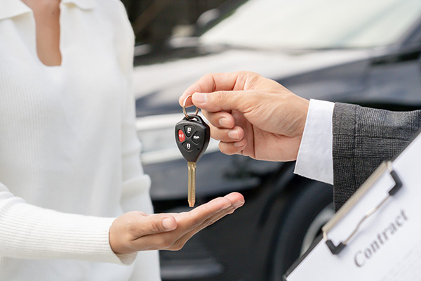 Eine Nahaufnahme des Kunden, der die Autoschlüssel vom Händler in einem Ausstellungsraum entgegennimmt.